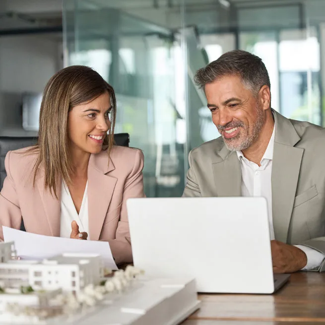 man and woman looking at computer with property model in foreground